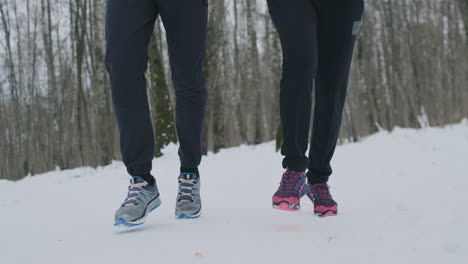 Close-up-of-the-feet-of-two-runners-in-sneakers-running-in-the-winter-in-the-park.-The-married-couple-goes-in-for-sports.